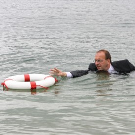 Drowning businessman struggling to reach a life preserver